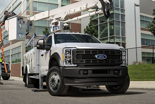 Workers moving machinery near 2023 Ford Super Duty® Chassis Cab with upfit at work site