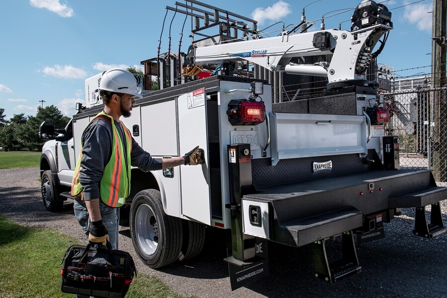 2023 Ford Super Duty® parked at the job site with a worker opening side panel
