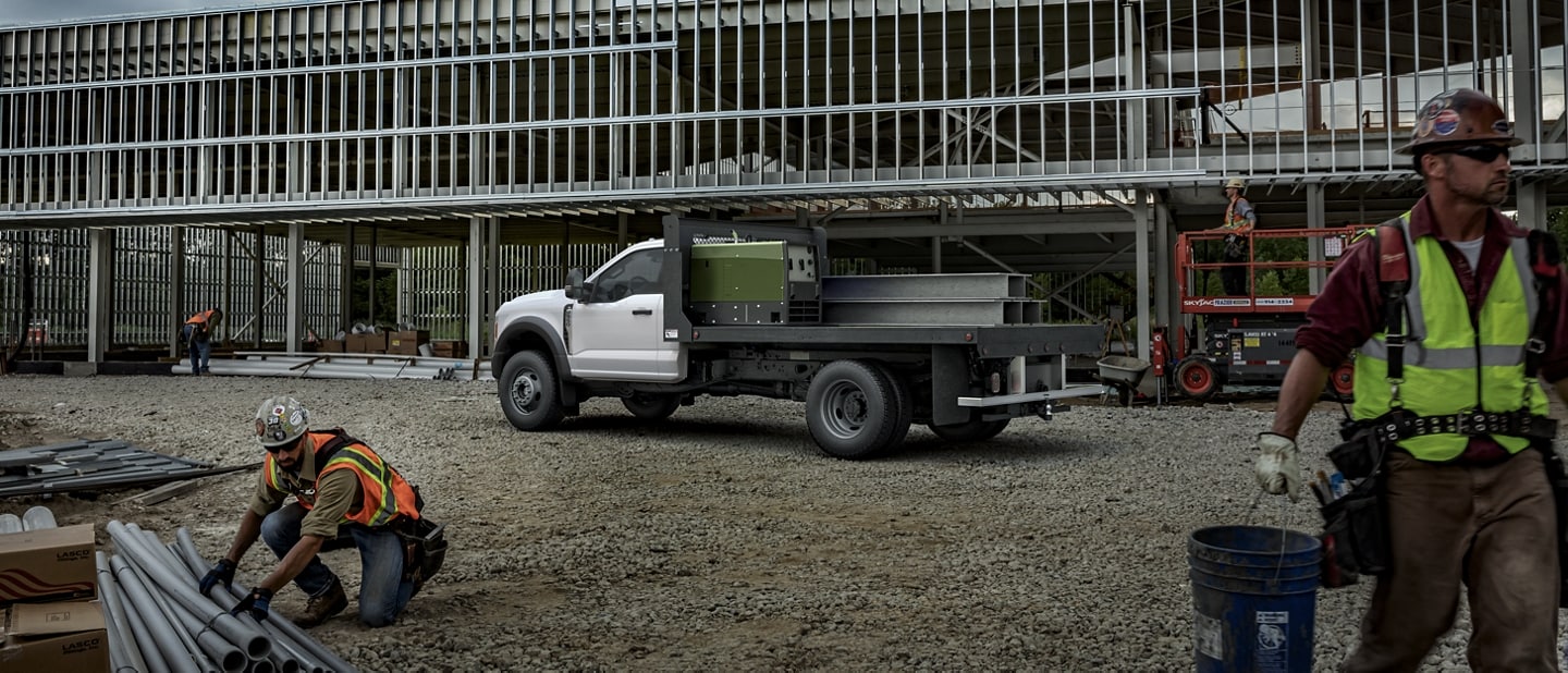 Construction workers working near 2024 Ford Super Duty® with crane upfit parked at worksite