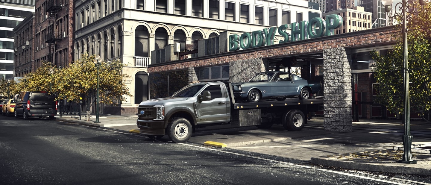 A 2024 Super Duty® F-600® Chassis Cab towing a classic car with the flatbed upfit