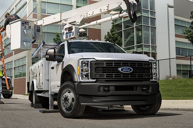 Workers moving machinery near 2024 Ford Super Duty® Chassis Cab with upfit at work site