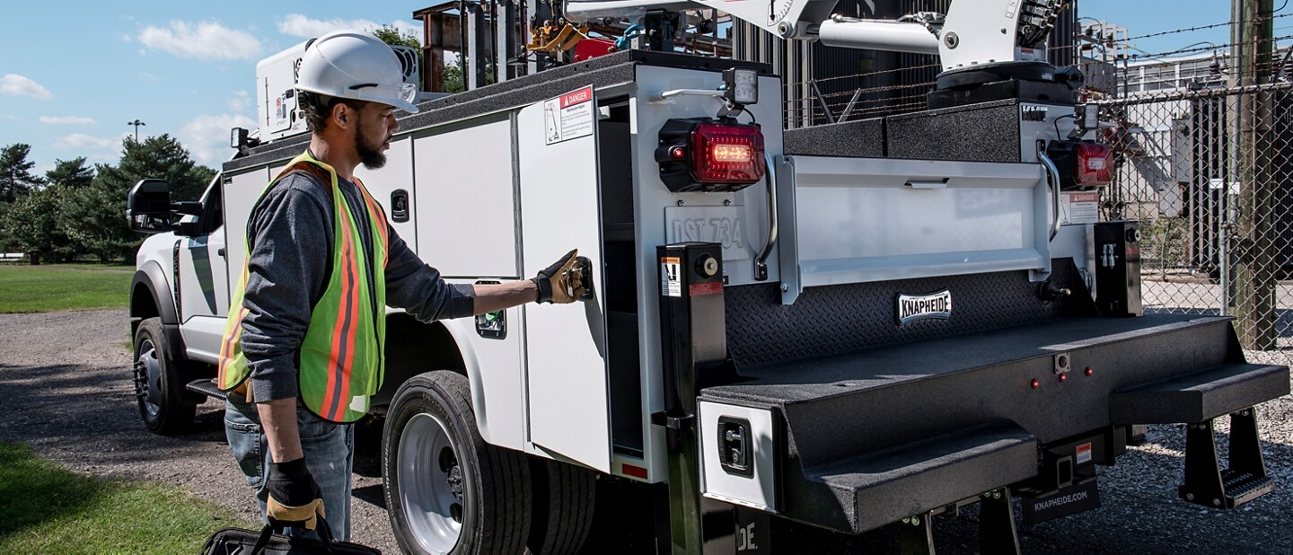 2024 Ford Super Duty® parked at the job site with a worker opening side panel