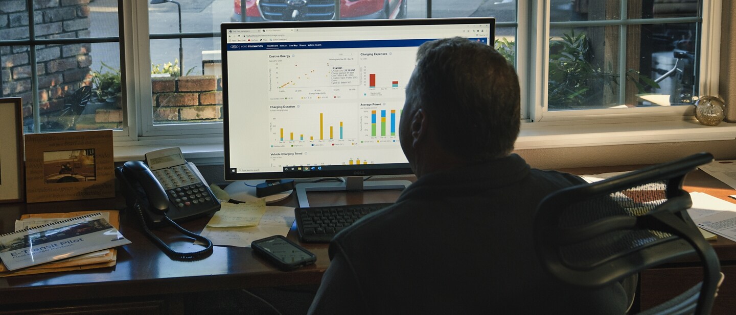 Man sitting at a computer looking at reports on the screen