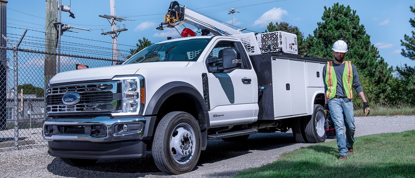 A worker walking away from a 2024 Super Duty® Chassis Cab parked on a gravel road.