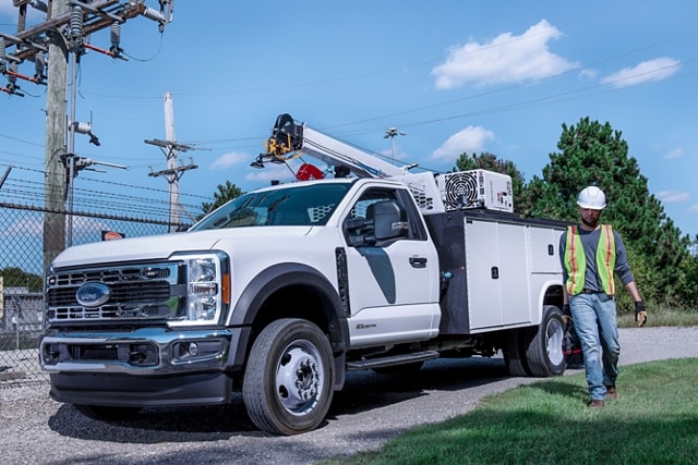 A worker walking away from a 2024 Super Duty® Chassis Cab parked on a gravel road.