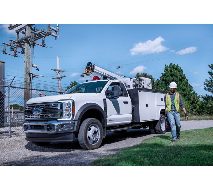 A worker walking away from a 2024 Ford Super Duty® Chassis Cab parked on a gravel road