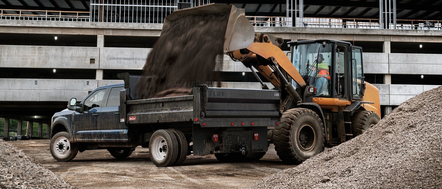 Dirt being poured into the back of a 2024 Ford Super Duty® Chassis Cab on a construction site