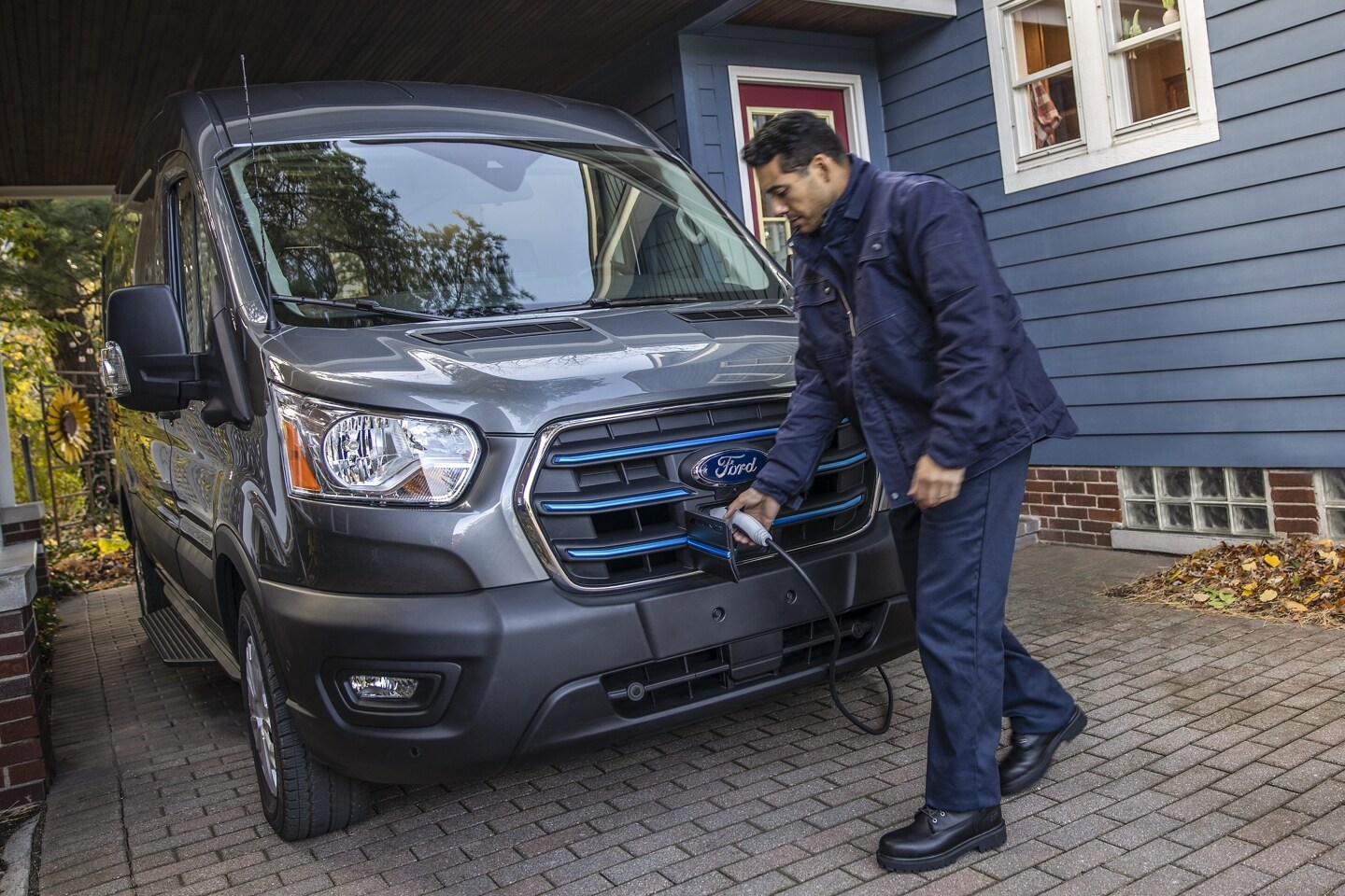 Man charging gray and blue 2024 Ford E-Transit Commercial utility van