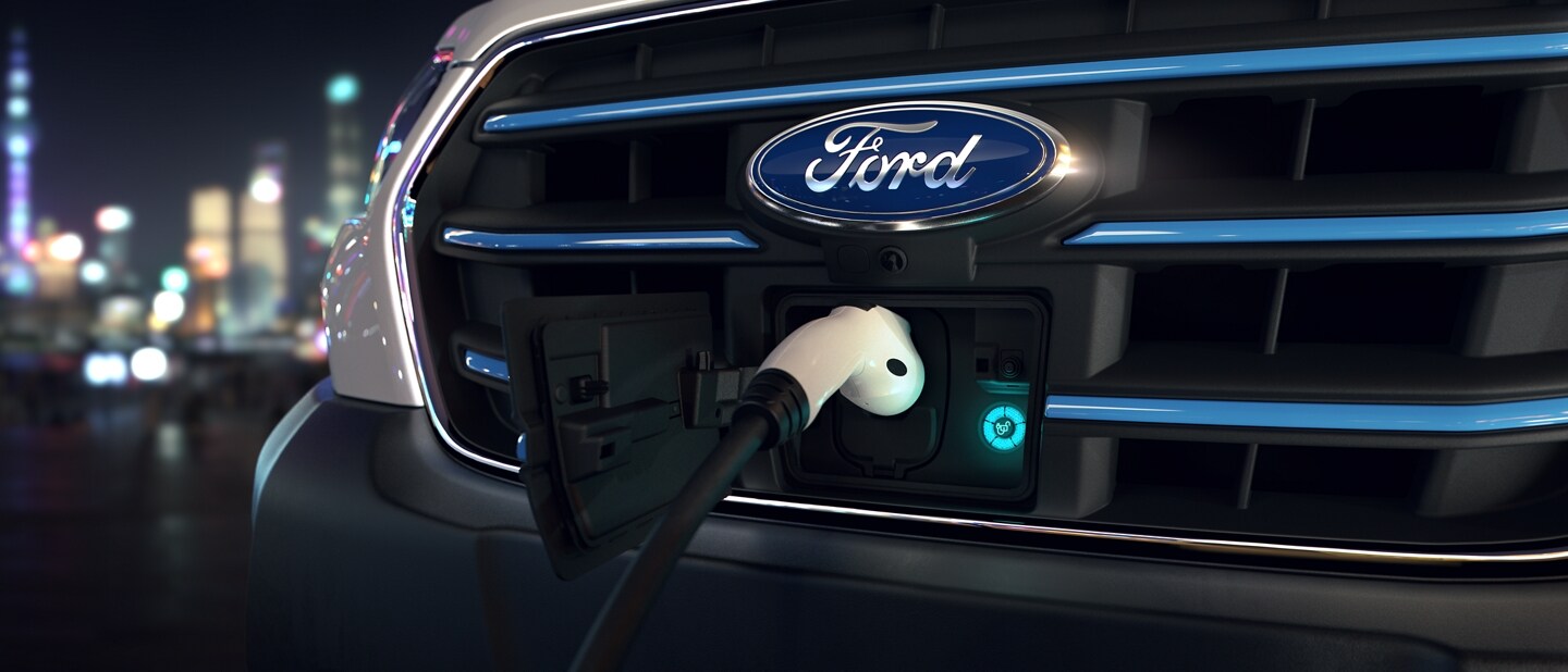 Primer plano de la parrilla con un cargador enchufado en la van Ford E-Transit™ 2023