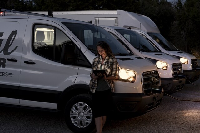 Una mujer parada afuera de la próxima flota de vehículos Ford E-Transit™ 2023