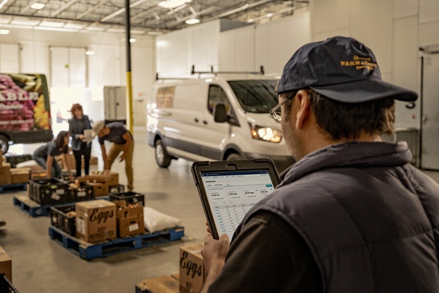 Man looking at clipboard while people unload boxes