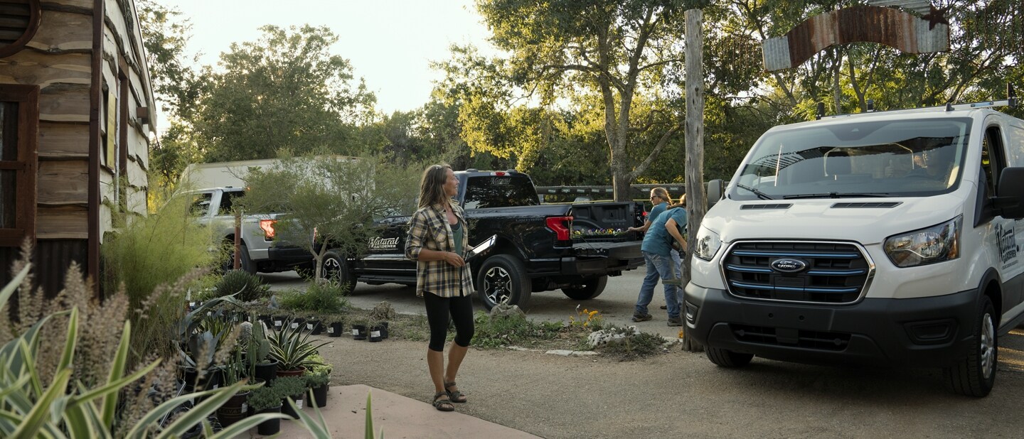 2023 Ford E-Transit™ parked in driveway with woman standing near it