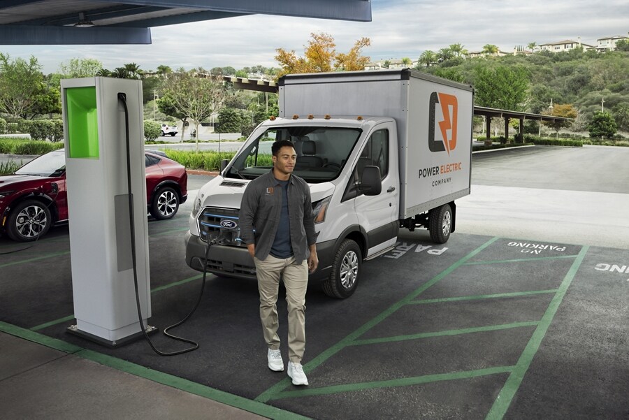 A man is standing in a parking lot while a vehicle is being charged