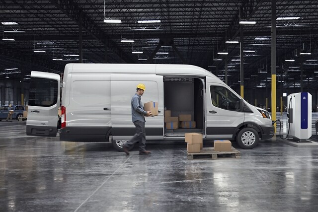 Un hombre cargando cajas en una cargo van Ford E-Transit™ 2023