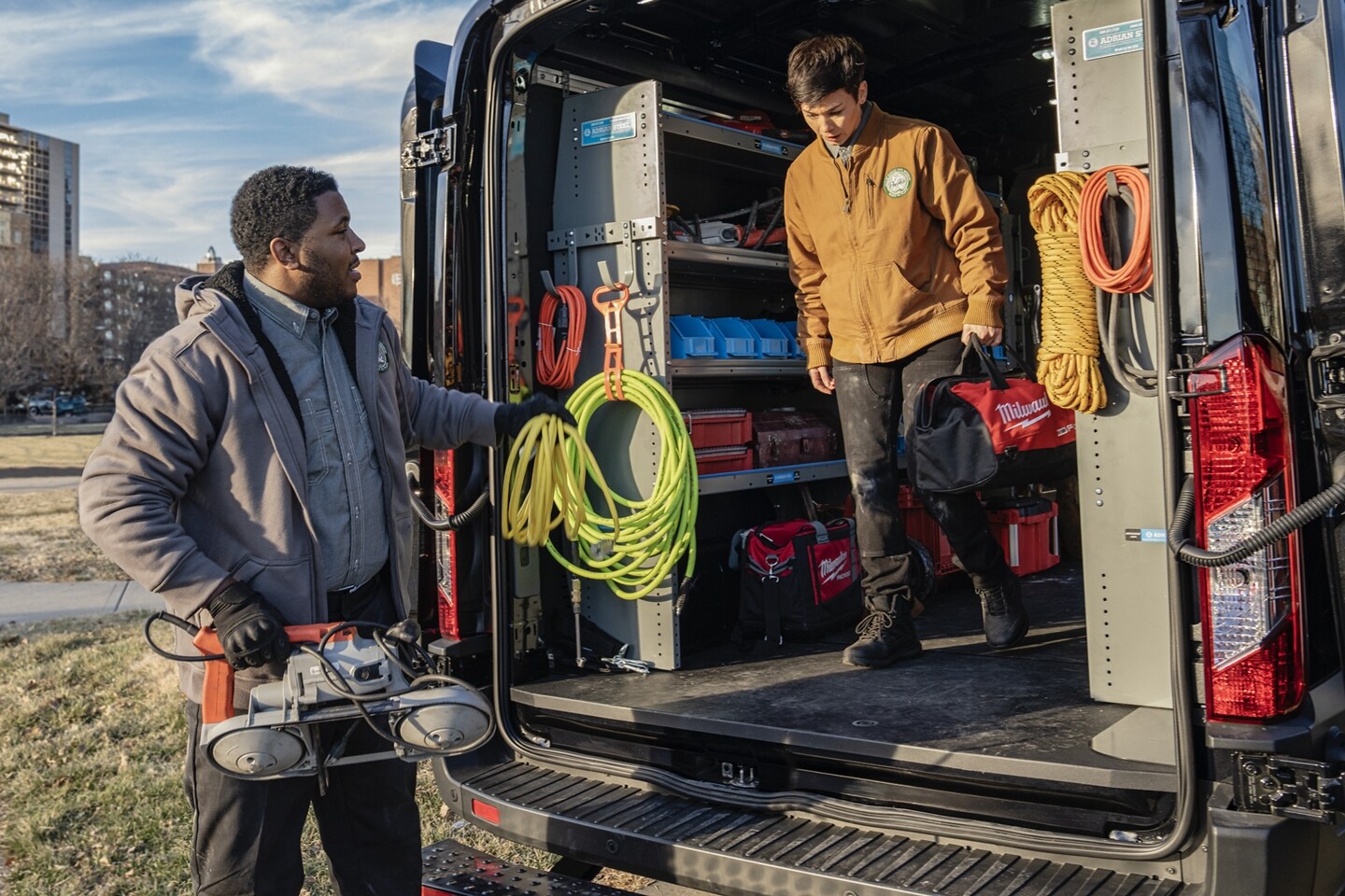 Two journey man electricians grabbing supplies out of the back of the 2024 Ford E-Transit.