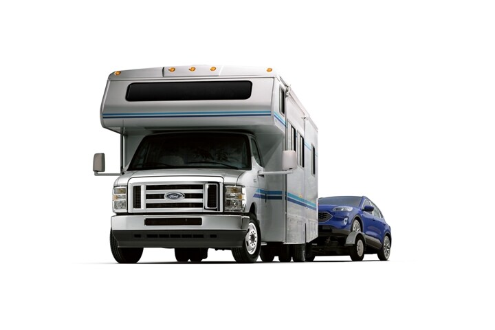 Una Ford E-Series Cutaway 2024 con ruedas traseras dobles con casa rodante Clase C remolcando un auto