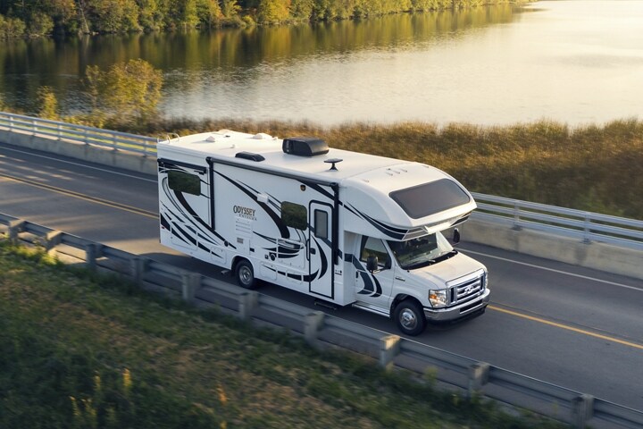 Una Ford E-Series Cutaway 2024 con ruedas traseras dobles, con casa rodante Clase C andando cerca de una gran extensión de agua