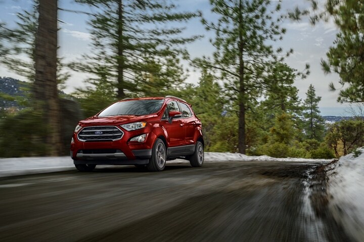 2021 Ford EcoSport in Ruby Red being driven on curved road near snow and large trees