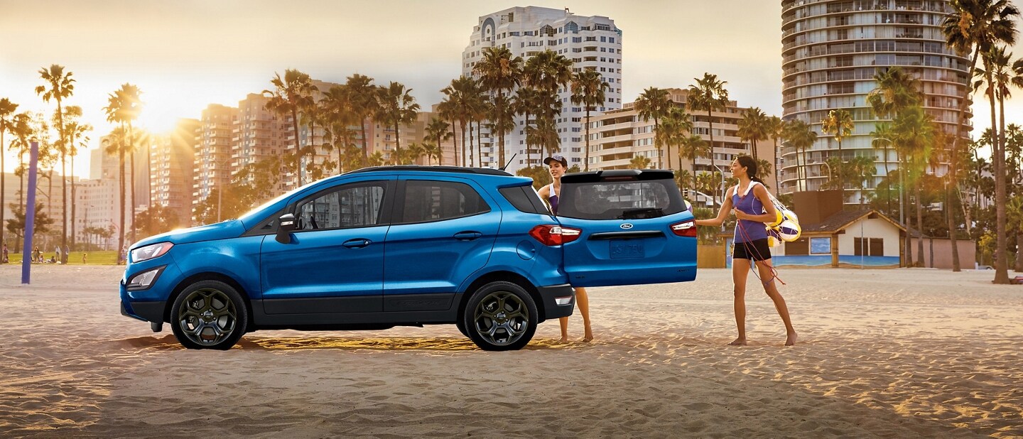 Two women loading beach gear into a 2021 Ford EcoSport S E S at the beach with the rear swing gate open