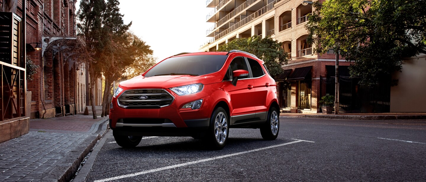 Una Ford EcoSport® 2022 en Race Red estacionada en un lugar cerca de edificios grandes en una ciudad