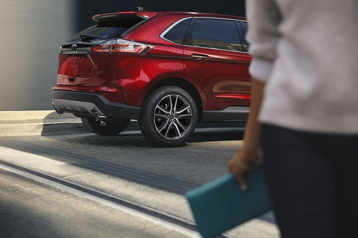 Una mujer que se aleja caminando de una Ford Edge 2022 en Rapid Red estacionada