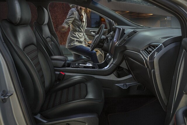 Interior of the front space of a 2022 Ford Edge with a woman getting into the driver’s seat