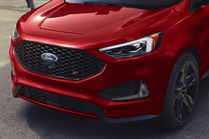 Hombre cruzando la calle hacia una Ford Edge 2022 en Rapid Red