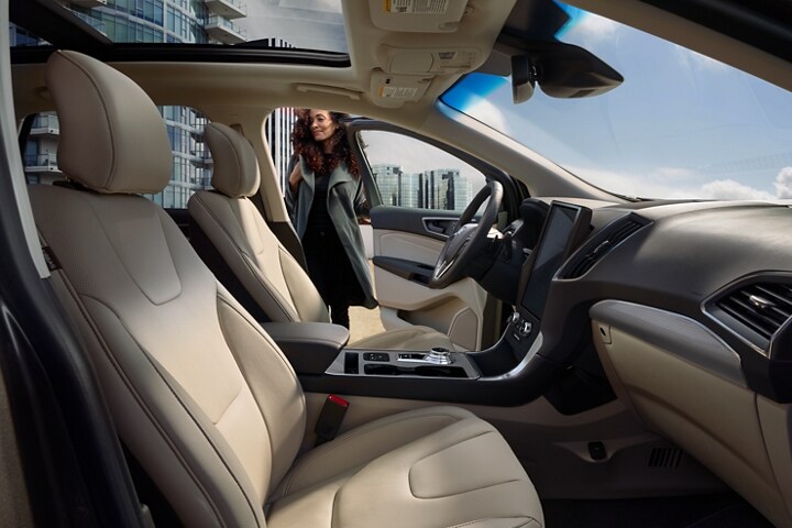 Interior de la Ford Edge Titanium 2022 con una mujer que cierra la puerta del lado del conductor