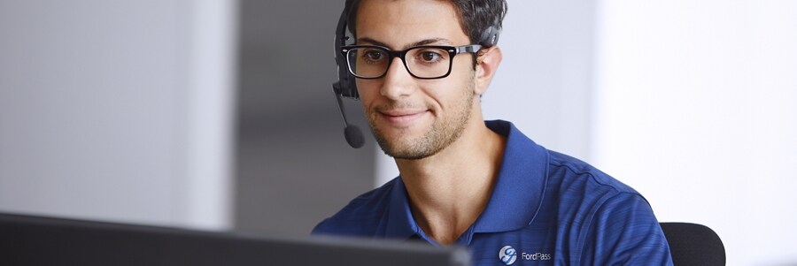 Hombre usando un auricular con micrófono sentado enfrente de la pantalla de una computadora