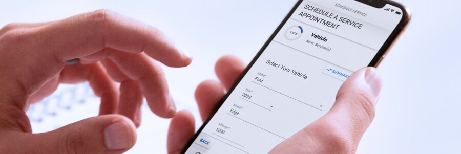 Una mano sosteniendo un smartphone que muestra el menú para Programar una Cita de Servicio en la Aplicación FordPass™