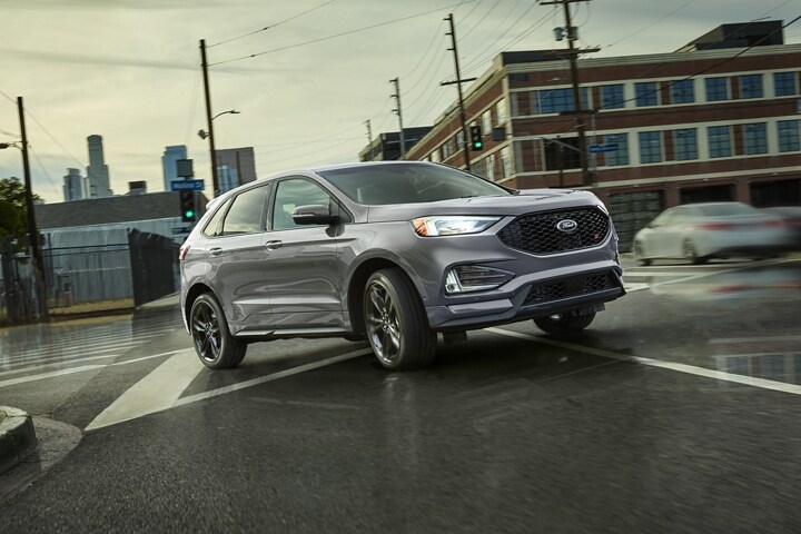 2023 Ford Edge® ST SUV in Iconic Silver turning right on a wet street