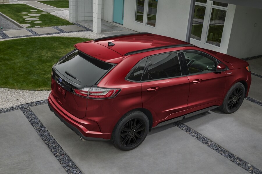 Una Ford Edge® ST 2023 en Rapid Red estacionada en la entrada de una casa