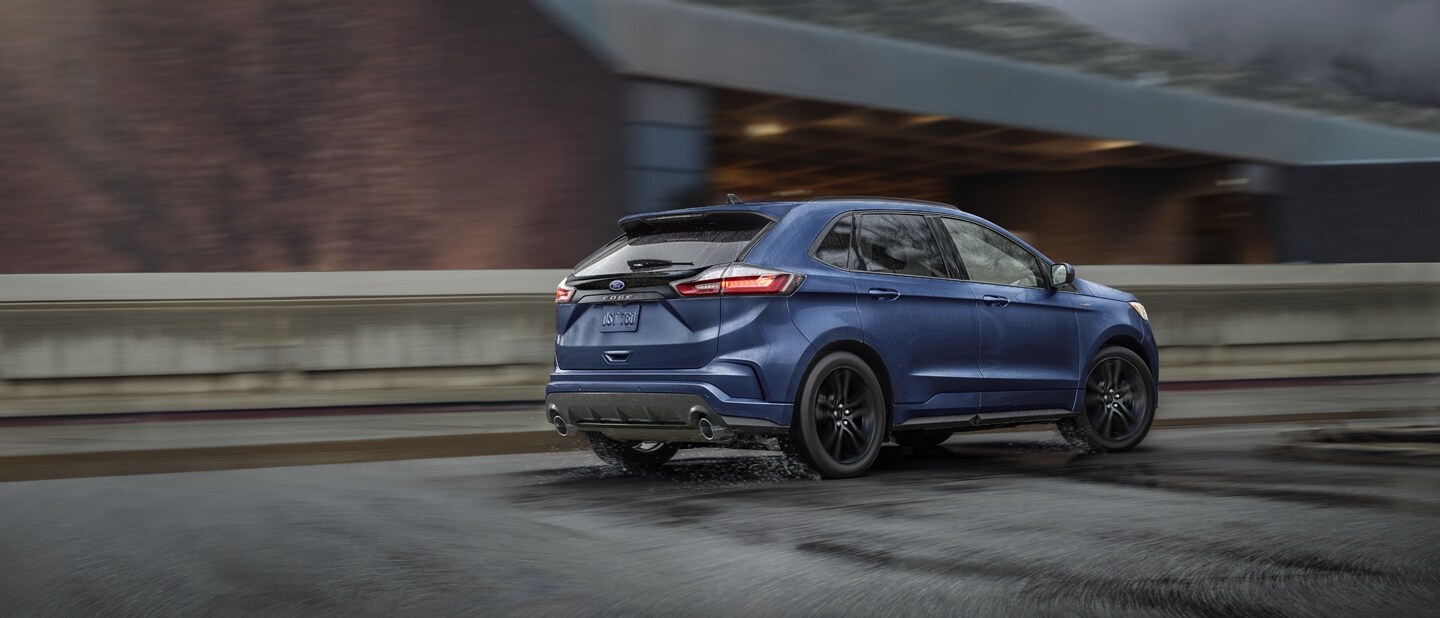 A 2023 Ford Edge® in Stone Blue being driven across an overpass