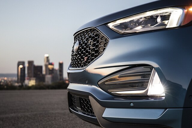 Close-up of bi-LED headlamps and fog lamps with city skyline in the background
