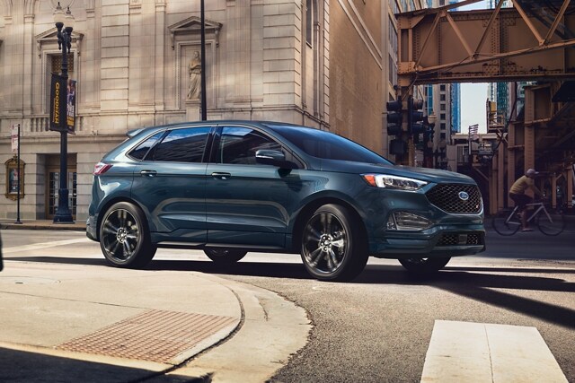 2023 Ford Edge® ST SUV in Stone Blue driving around a curve in a city