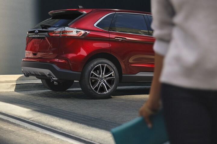 Woman walking away from a parked 2023 Ford Edge® SUV in Rapid Red