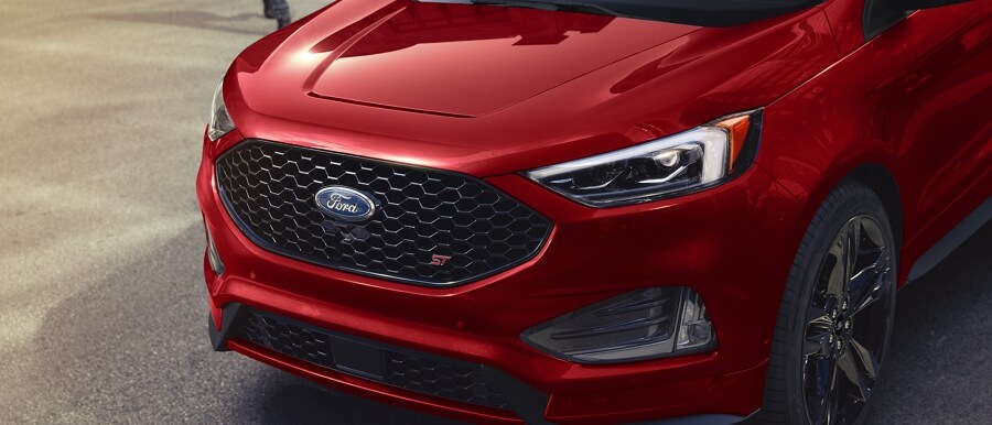 Grille and driver’s side headlamp of a 2023 Ford Edge® ST SUV in Rapid Red