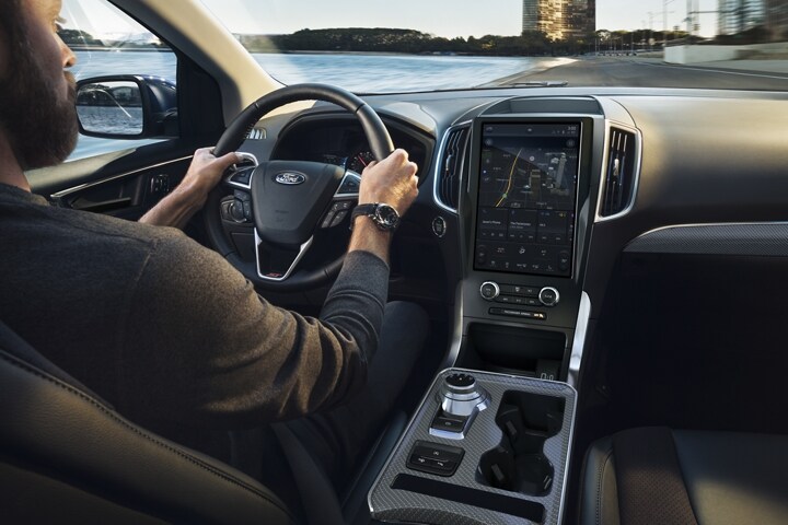 Interior of a 2023 Ford Edge® as a man drives and looks at interior console