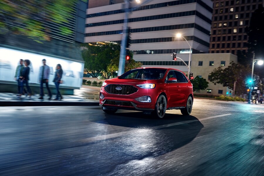 2023 Ford Edge® SUV in Rapid Red being driven in a city at night