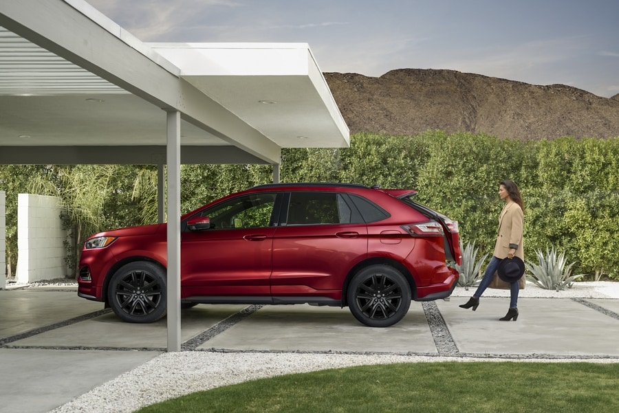 Woman carrying two bags activates the hands-free liftgate on a 2024 Ford Edge®
