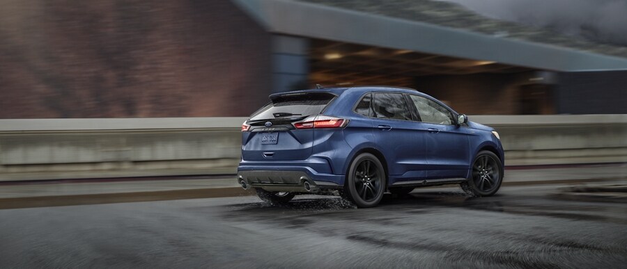 A 2024 Ford Edge® in Stone Blue being driven across an overpass
