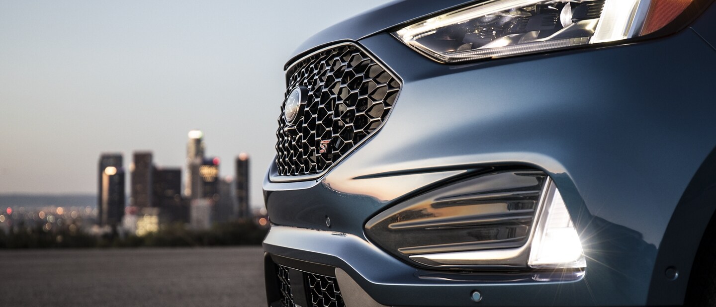 Close-up of bi-LED headlamps and fog lamps with city skyline in the background