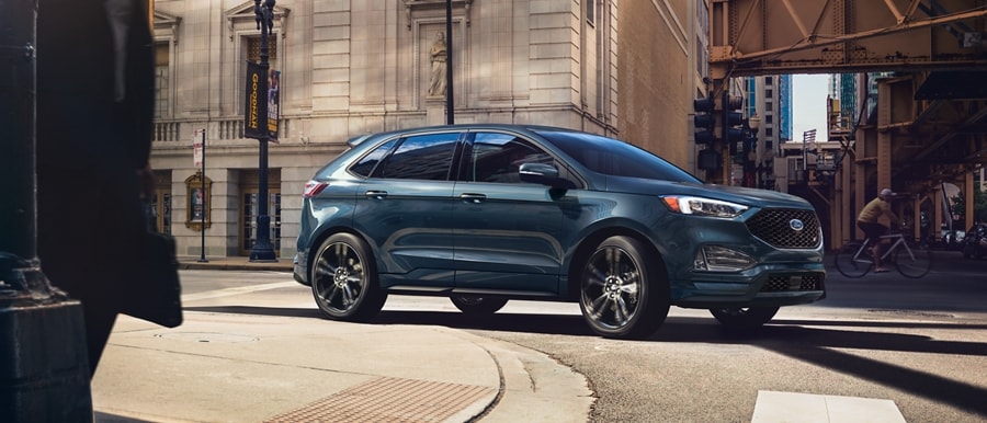 2024 Ford Edge® ST model in Sone Blue driving around a curve in a city