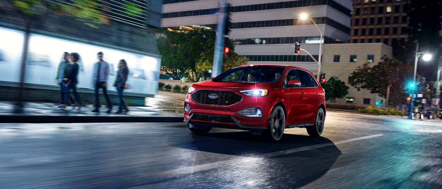 2024 Ford Edge® SUV in Rapid Red being driven in a city at night