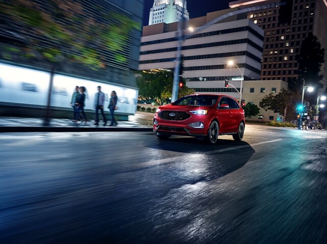 2024 Ford Edge® SUV in Rapid Red being driven in a city at night