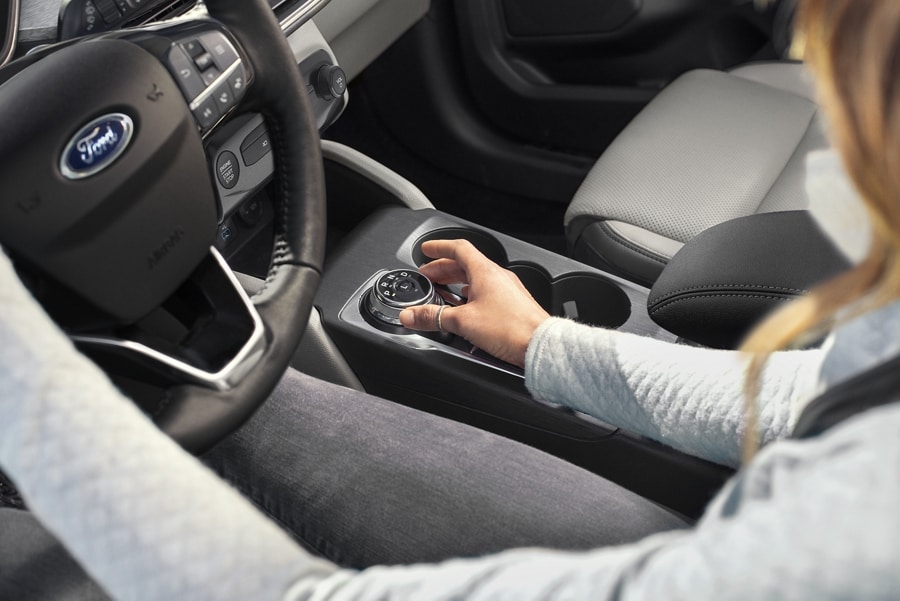 Vista del interior de la Ford Escape® 2023 con el conductor utilizando el dial giratorio en palanca de cambios estándar