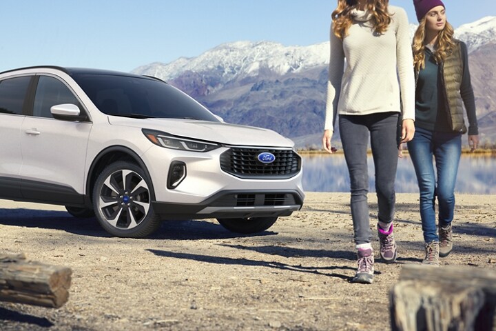2023 Ford Escape® in Snow White parked in front of mountain lake with two girls