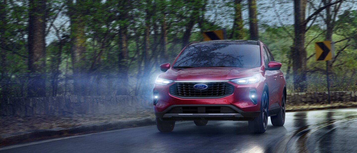 Una Ford Escape® 2023 en Rapid Red Metallic Tinted Clearcoat andando por una carretera mojada de noche