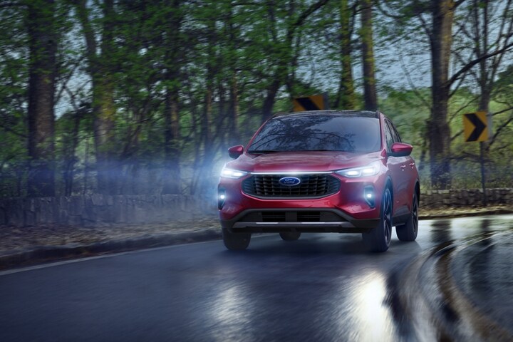 2023 Ford Escape® in Rapid Red Metallic Tinted Clearcoat being driven down a dark wet road