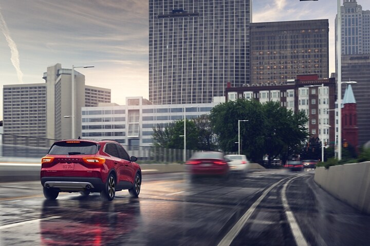 2023 Ford Escape® in Rapid Red Metallic Tinted Clearcoat being driven down a wet city road